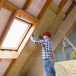 Man installing thermal roof insulation layer – using mineral wool panels. Attic renovation and insulation concept